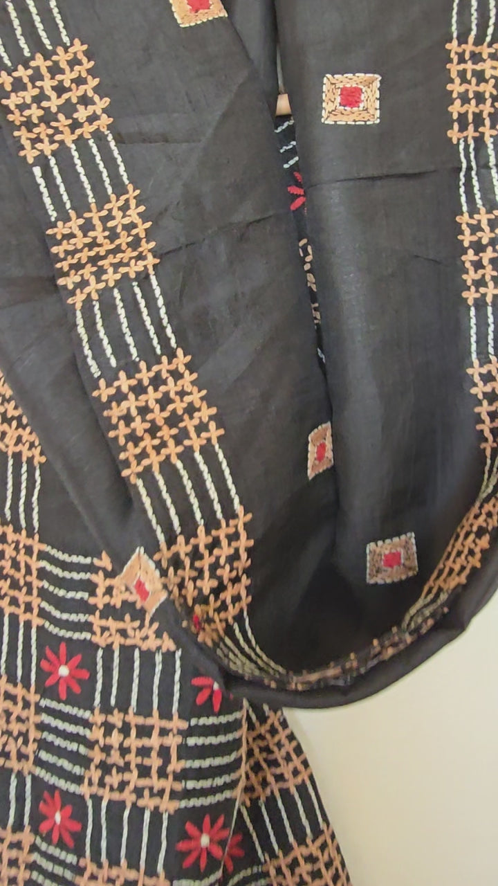Close-up of kantha embroidery stitching on black silk fabric showing geometric pattern detail